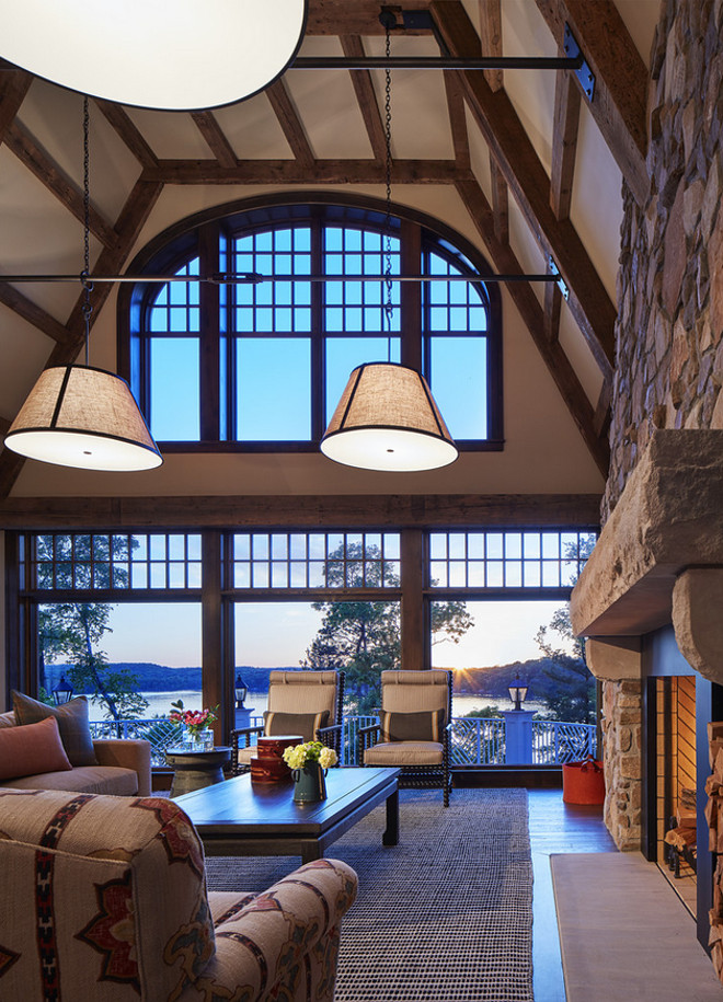 Living room ceiling beams. Rustic lake house living room with ceiling beams and stone fireplace. Floor-to-ceiling windows frame the stunning view. Lake house living room ceiling beams #ceilingbeams #livingroom #lakehouse #beams John Kraemer & Sons