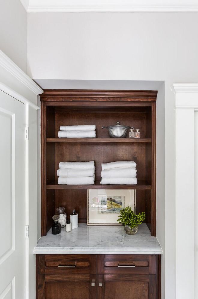 Bathroom linen cabinet. Stained cabinets add warmth to the clean white marble palette. Marie Flanigan Interiors