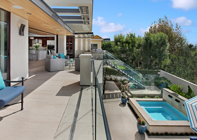 Contemporary home deck with glass railings, steel and glass staircase, skylight, glass folding patio doors and hidden outdoor heaters. Brandon Architects, Inc.