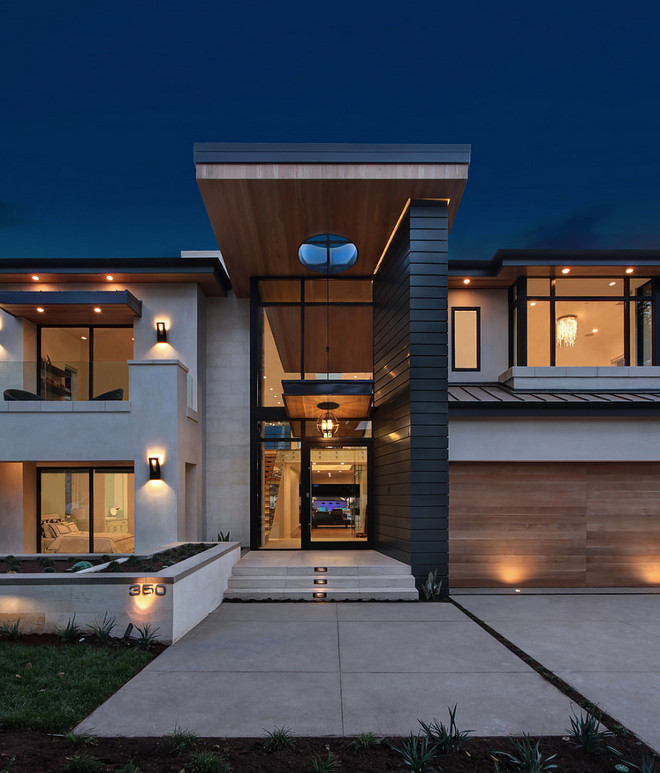 Contemporay Home Exterior with glass entry, metal roof, black windows and black steel door, shiplap style siding and modern wood garage door. Brandon Architects, Inc.