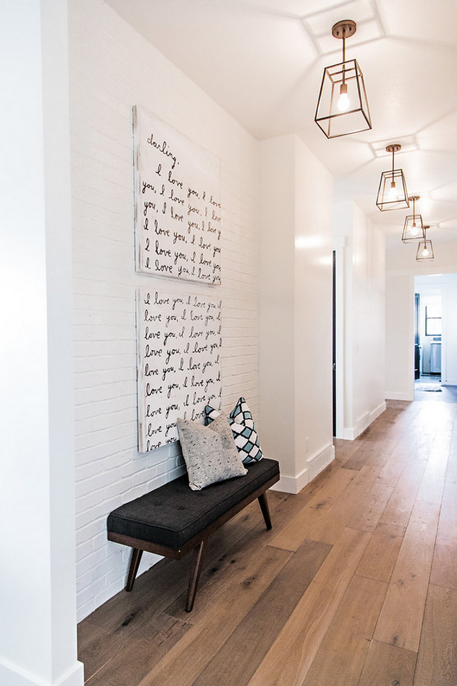 Hardwood Floor and painted brick accent wall. Hall features wide plank white oak hardwood floors, painted brick accent wall and brushed brass lantern lighting. #hardwoodfloor #paintedbrick #brickwall #accentwall Sita Montgomery Interiors