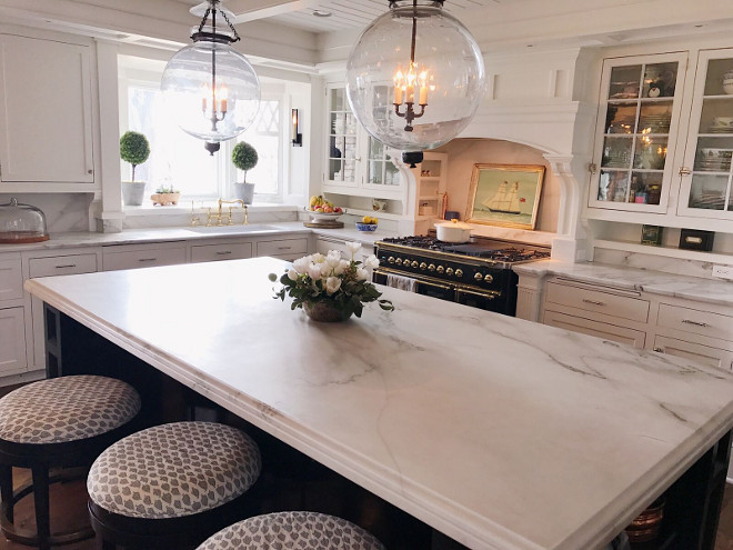 Classic white kitchens. White Carrera marble on countertops and backsplash, Silver hardware on cabinets. Tempered antique glass in upper cabinets. Island measures 106 by 54' and is painted Benjamin Moore black with antique brass pulls. Kitchen faucet is gold and with a farm house sink. I love mixing metals in a kitchen. Black and brass stove is ILVE and I love its form and function. Star pendant lights are antiques from Nantucket. #classickitchens #classicwhitekitchens #kitchen Beautiful Homes of Instagram @SweetShadyLane