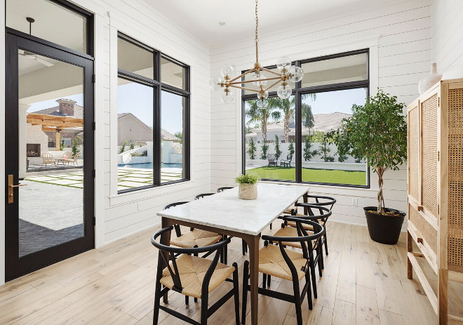 Minimalist Modern farmhouse dining room with shiplap walls, bleached hardwood floors and modern glass and rope chandelier. This minimalist modern farmhouse dining room features shiplap walls, black windows and patio doors, wishbone dining chairs, marble top dining table, bleached hardwood floors and modern glass and rope chandelier #minimalistmodernfarmhouse #modernfarmhouse #diningroom #shiplapwalls #shiplap #blackwindows #blackpatiodoors #wishbonediningchairs #marbletopdiningtable #bleachedhardwoodfloors #modernglassandropechandelier A Finer Touch Construction