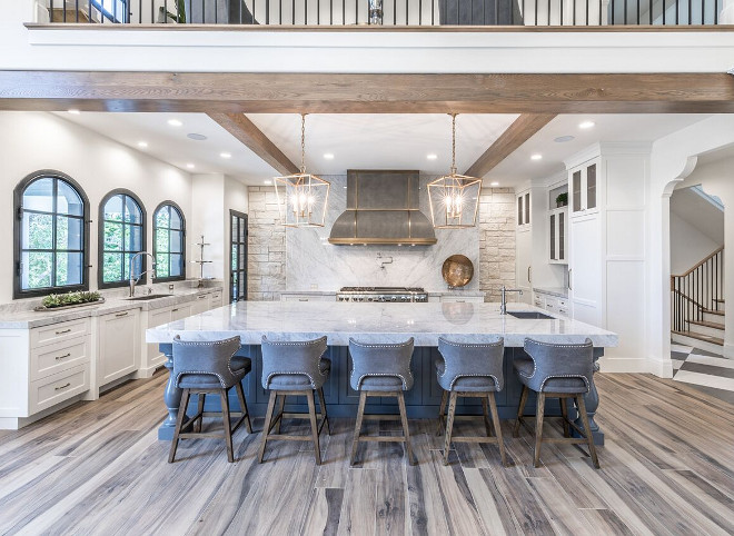 White kitchen with zinc hood, grey kitchen island and arched black windows. Tree Haven Homes & Danielle Loryn Design