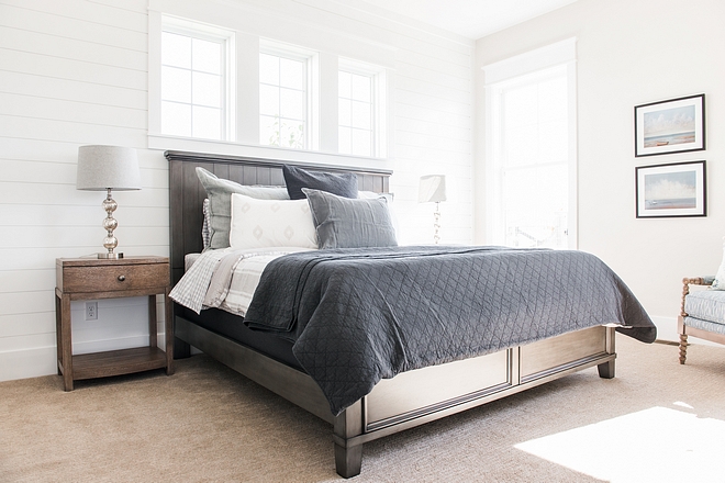 This bright bedroom features shiplap and a neutral carpet flooring