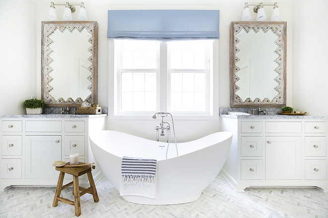 In the master bathroom, a freestanding bathtub is flanked by his and hers vanities