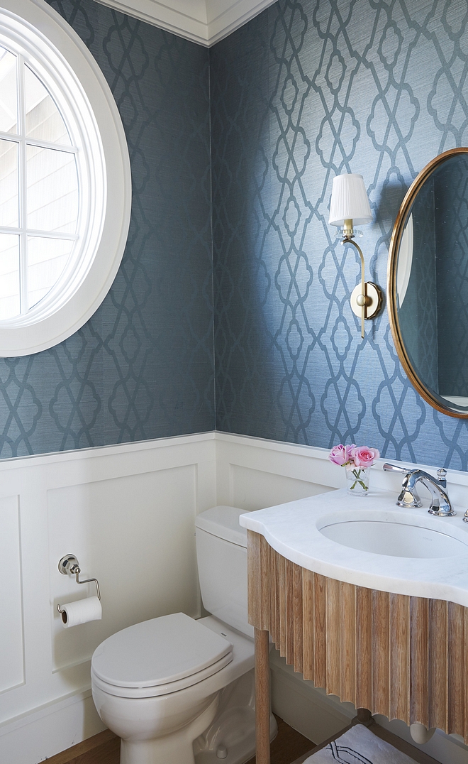 The powder room features a stunning custom White Oak vanity with white marble countertop, wall paneling and a blue wallpaper