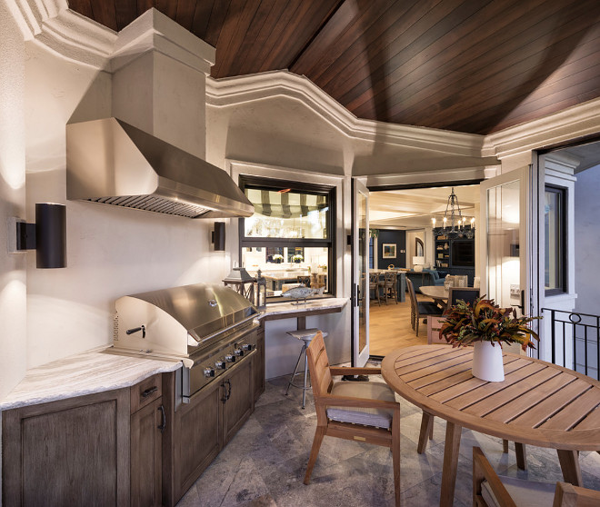 Kitchen doors open to an outdoor patio with built in bbq and teak dining furniture