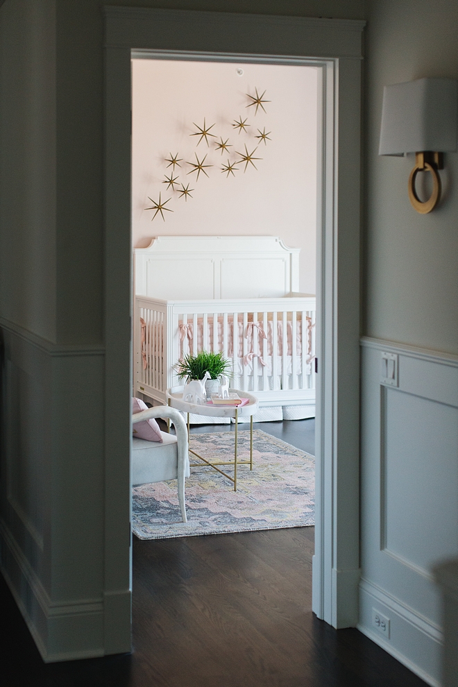 A grey hallway, painted in Benjamin Moore Classic Gray, leads to a blush pink nursery