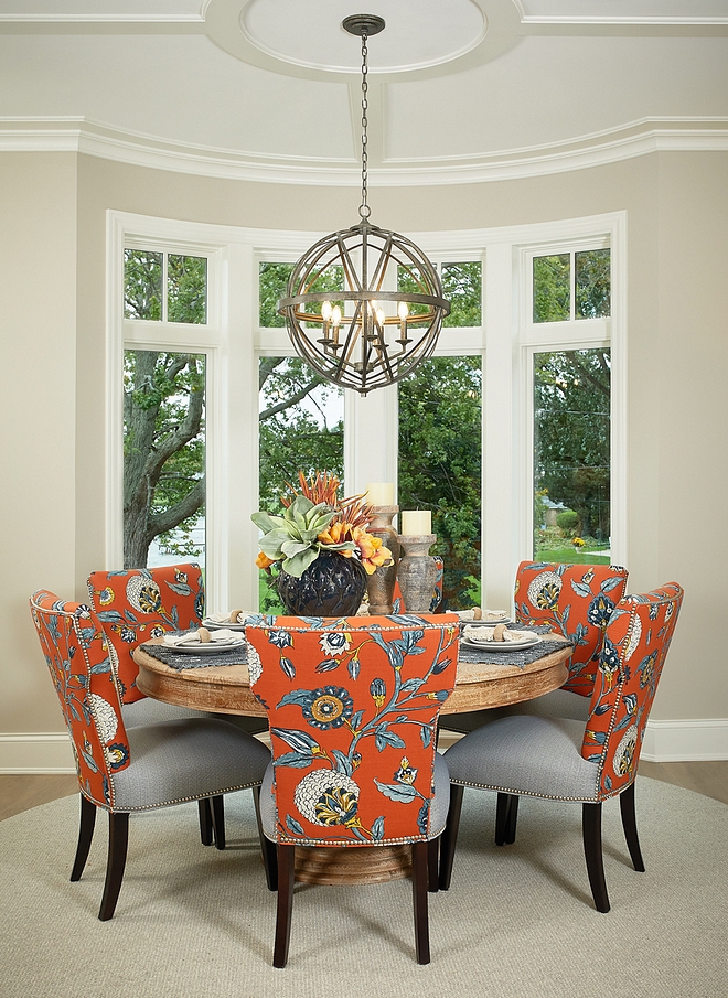 Dining room features a round dining table sisal rug and dining chairs with floral fabric Lighting source on Home Bunch #diningroom