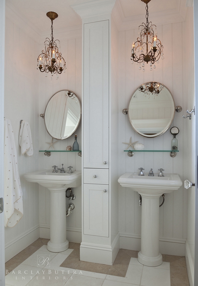This bathroom features board and batten wall paneling and pedestal sinks with a built-in cabinet in the center Wall paint color is Satin White Valspar