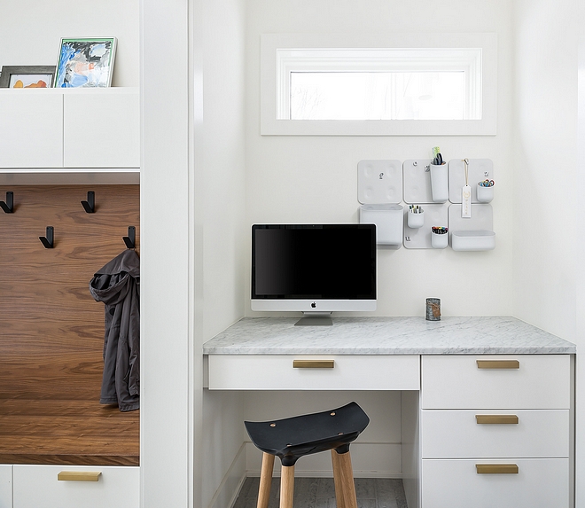 The mudroom features a custom desk with Carrara marble countertop On the left you will find the mudroom with Walnut bench