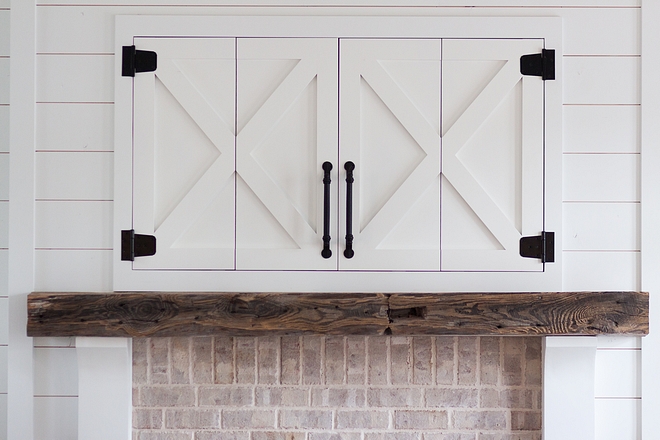 Barn door tv cabinet above fireplace The TV is concealed in the custom farmhouse-inspired cabinet above the fireplace source on Home Bunch