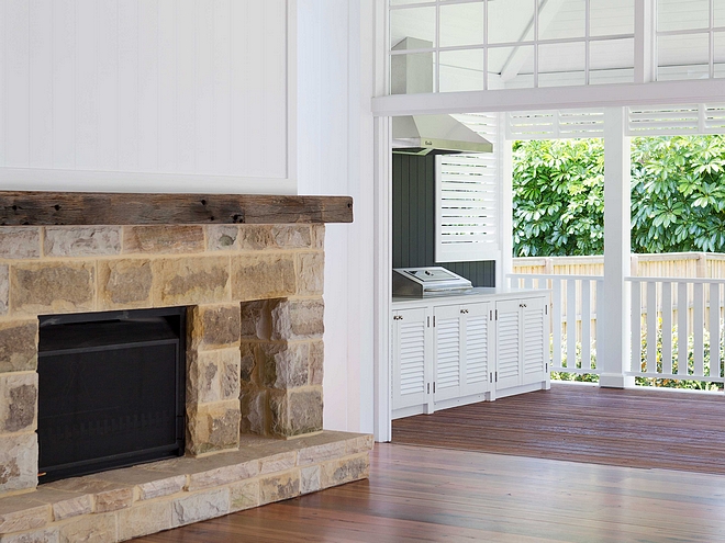 Living room with stone fireplace opens to back porch with outdoor kitchen