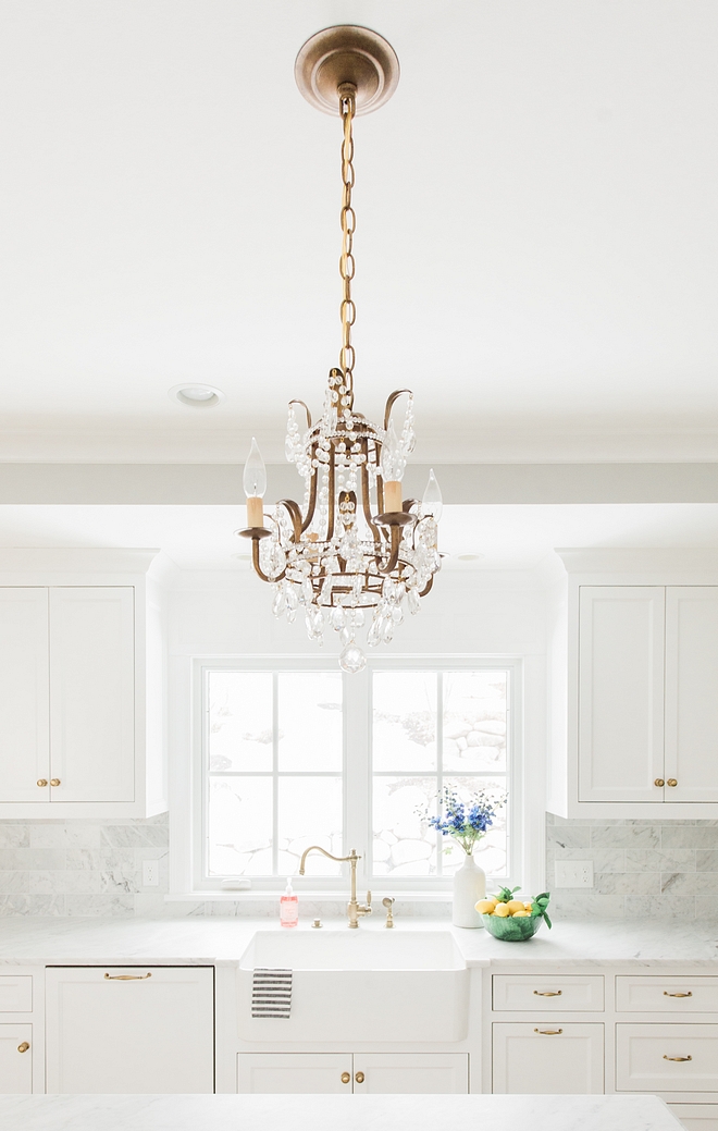 Kitchen Hardware Knobs and pulls Brass antigue English brass against white kitchen cabinets and antique brass chandelier over kitchen island