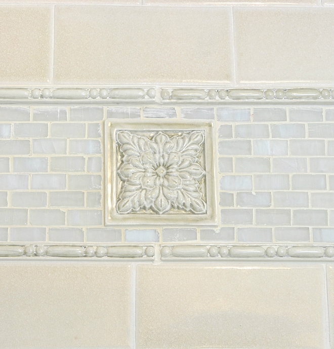 Iridescent blue-ish grey mosaic tile It not only lines the upper trim of the shower but it also makes up the entire flooring of this bathroom