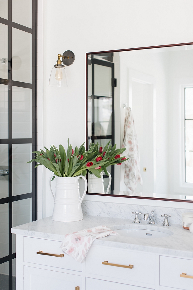 Bathrom with white vanity with white marble countertop glass sconce and black steel shower all sources on Home Bunch