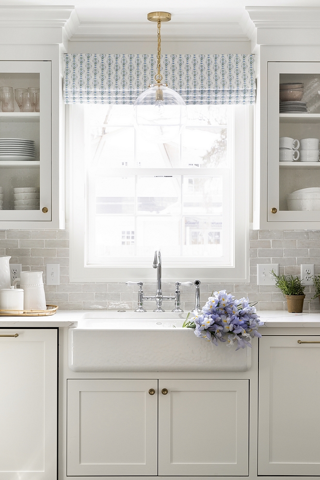 Soft white kitchen with white terracotta subway tile backsplash white quartz countertop and white farmhouse sink all sources are shared on Home Bunch #softwhitekitchen #kitchen #terracottasubwaytile #backsplash #whitekicthen