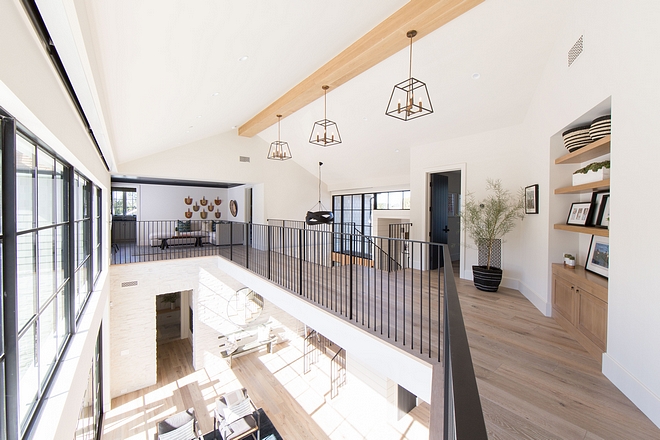 Staircase opens to a bridge with custom iron railing