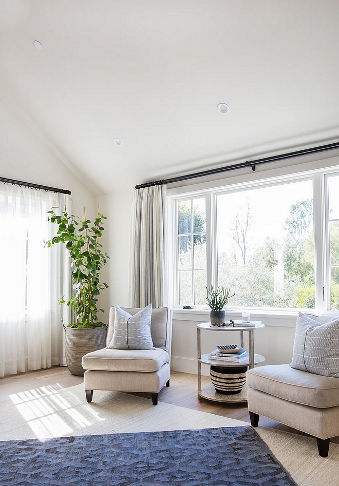 Bedroom sitting area with two accent chairs, custom draperies with Stark Casamance Azur fabric and round accent wood table #bedroom #sittingarea