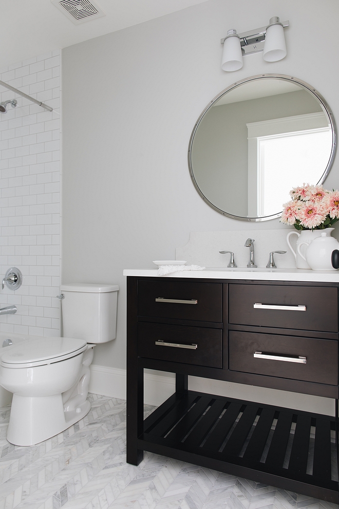 This bathroom is a perfect combination of masculine and feminine with a dark wood cabinet from RH next to a Chevron Carrara marble floor Countertop Misty Carrera Honed Backsplash is 8” tall with scallop edge