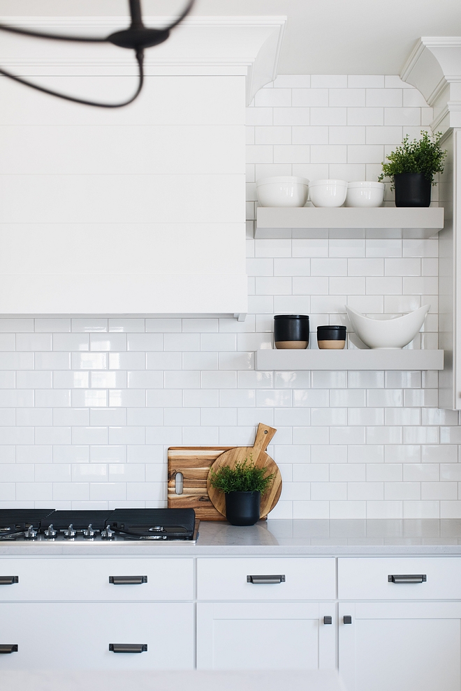 White kitchen with white subway tile backsplash and grey floating shelves to add contrast The grey floating shelves are painted in Ozark Shadows by Benjamin Moore #floatingshelves #kitchenfloatingshelves #OzarkShadowsBenjaminMoore