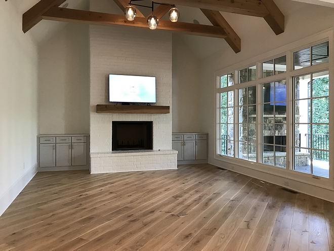 Modern Farmhouse family room features exposed trusses ceiling and a painted brick fireplace #modernfarmhouse #familyroom #exposedtrusses #trussesceiling #trusses #paintedbrickfireplace