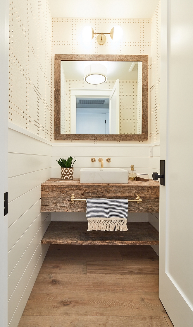 Farmhouse Farmhouse-style bathroom features half wall shiplap wainscoting with wallpaper above, wide plank hardwood flooring, reclaimed wood mirror, wall-mounted faucet, vessel sink and reclaimed wood freestanding vanity with shelf for baskets #farmhousebathroom #farmhouse #bathroom #shiplapwainscoting #reclaimedwood #freestandingvanity