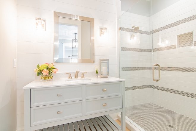 Bathroom with white shiplap accent wall painted in SW Extra White light grey vanity and shower with striped tile design #bathroom