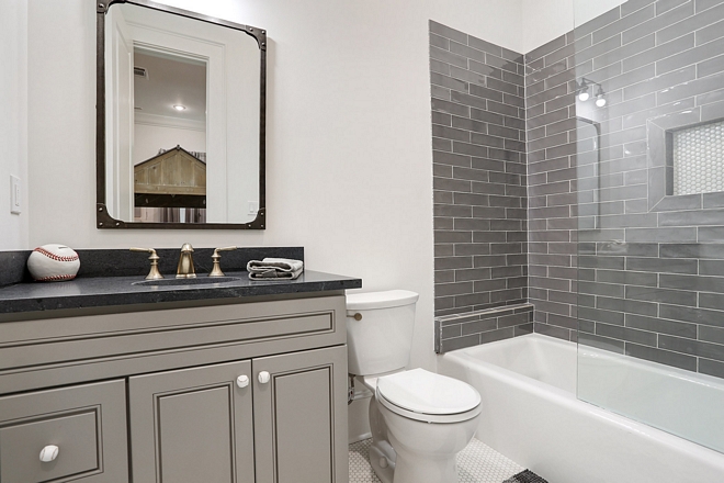 Boys bathroom with black countertop, grey vanity and charcoal grey subway tile