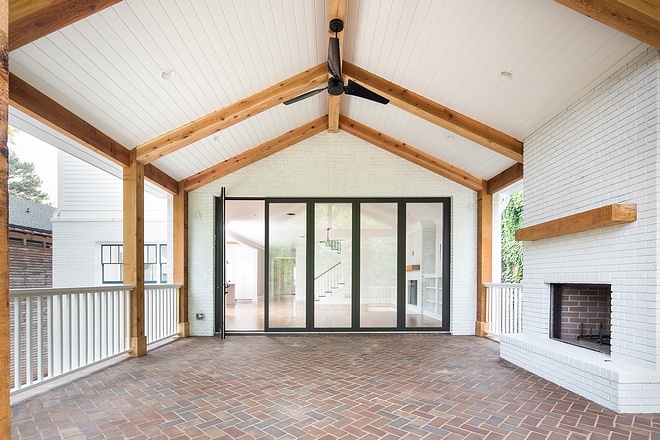 Farmhouse Outdoor Living Area This covered outdoor living space features vaulted ceiling with tongue and groove and beams, painted brick fireplace and brick flooring in a herringbone pattern #farmhouse #outdoorfarmhouse #paintedbrick #tongueandgroove #brick #herringbonebrick