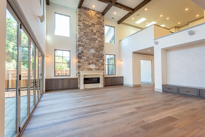 Great Room Design Inspiration The kitchen opens to a large Great Room with high ceiling, tall fireplace and custom media cabinetry #Greatroom