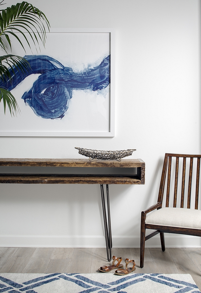 Foyer with midcentury console table with wood top and metal base, abstract artwork, blue and white rug and modern newel accent chair #foyer #midcentury #art #furniture #chair #rug