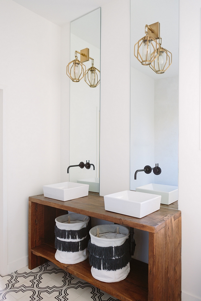 Transitional bathroom features a custom wooden console table used as vanity, vessel sinks and a pair of Moroccan embellished hampers Console table is better if made of solid hardwood - it would make a great DIY #transitionalbathroom #bathroom #vesselsink #Moroccanhamper