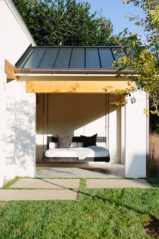 Modern Farmhouse with metal roof, stucco exterior painted in Benjamin Moore OC-17 White Dove, Cedar Beams and a wooden porch swing #ModernFarmhouse #stucco #BenjaminMooreOC17WhiteDoveexterior #porchswing