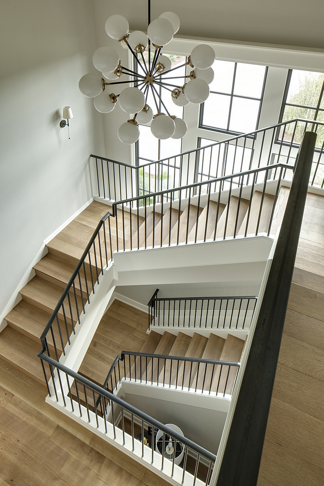 This gorgeous staircase features White Oak wood treads and wood risers. The metal railing is custom. Window sashes Sherwin Williams Medium Bronze #staircase #whiteoak #metalrailing