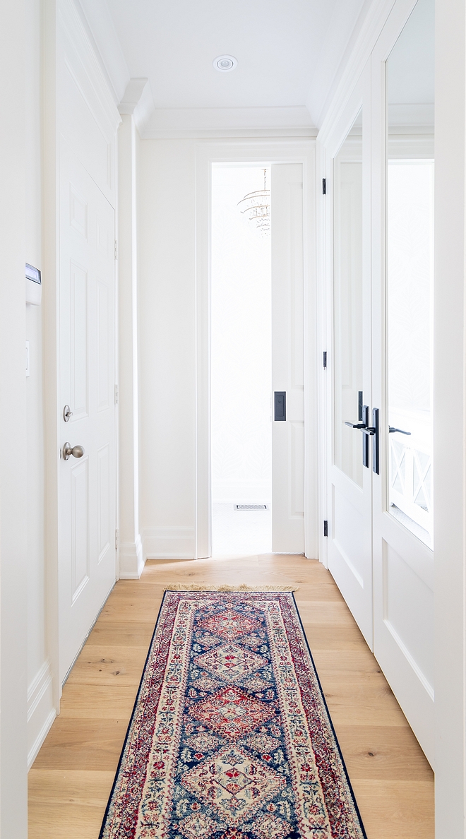 Hallway with closet with mirrored doors and vintage hall runner All of the wainscoting and millwork is painted Benjamin Moore Simply White same as the wall colour #hall #hallway #millwork #BenjaminMooreSimplyWhite