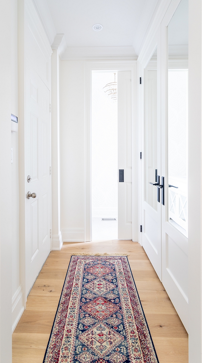 Hallway with closet with mirrored doors and vintage hall runner All of the wainscoting and millwork is painted Benjamin Moore Simply White same as the wall colour #hall #hallway #millwork #BenjaminMooreSimplyWhite