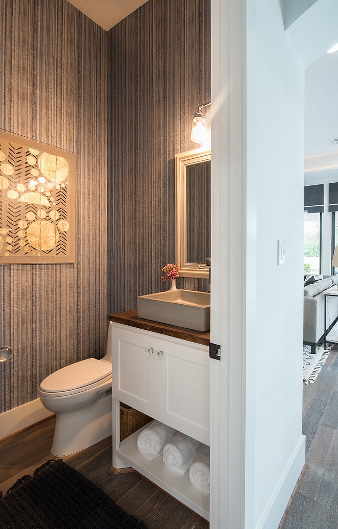 The powder room features a custom vanity with concrete vessel sink and a transitional grasscloth wallpaper #Powderroom #concretevesselsink #vesselsink #Bathroom