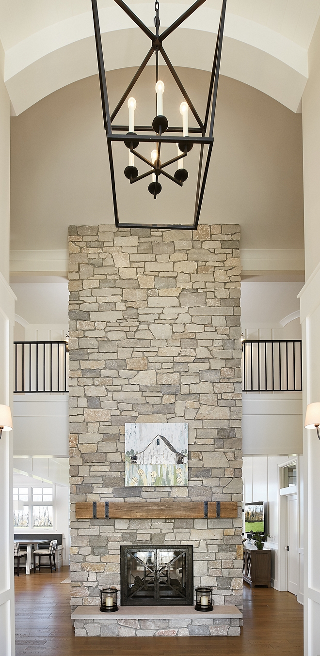 Two story fireplace Stone Fireplace This two-story stone double-sided fireplace is surround with raised natural stone hearth and rustic mantel beams #Twostoryfireplace #StoneFireplace #naturalstonefireplace