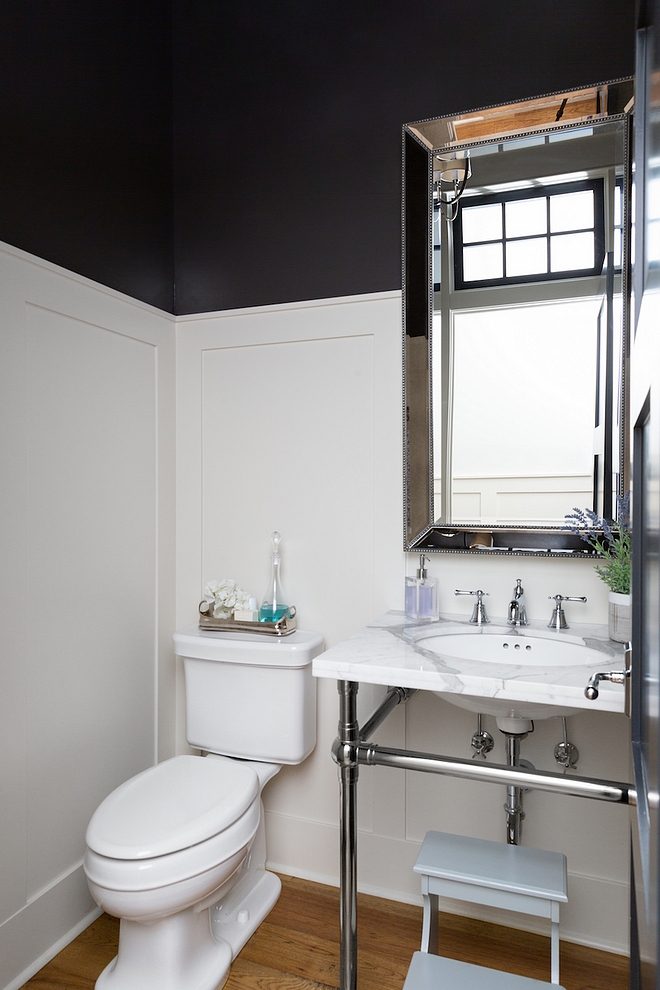 The powder room features a classic marble washstand with metal base and wall paneling #poderroom #paneling #bathroom #wainscotting #washstand