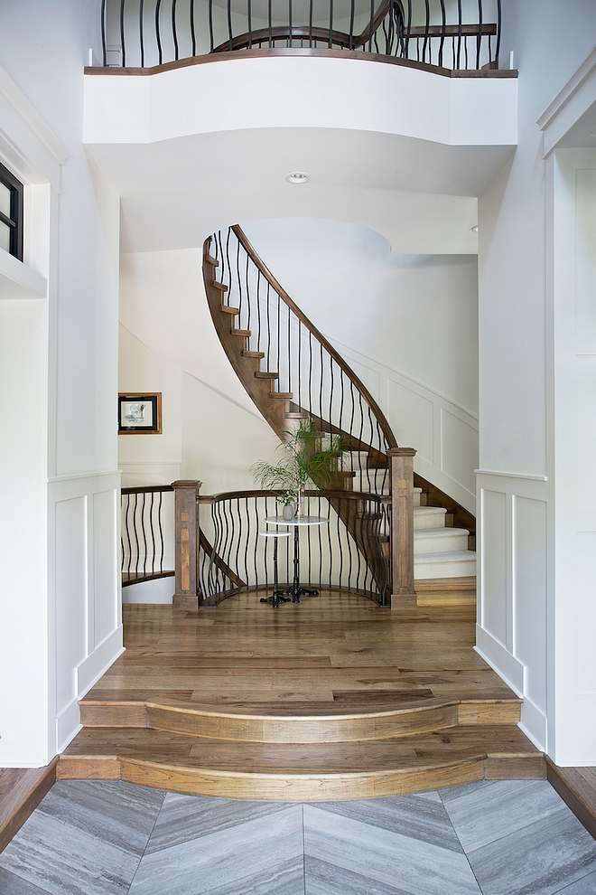 Foyer with grey Limestone in a chevron pattern and elevated hardwood flooring leading to a spiral staircase #foyer #chevronflooring #hardwoodflooring #spiralstaircase