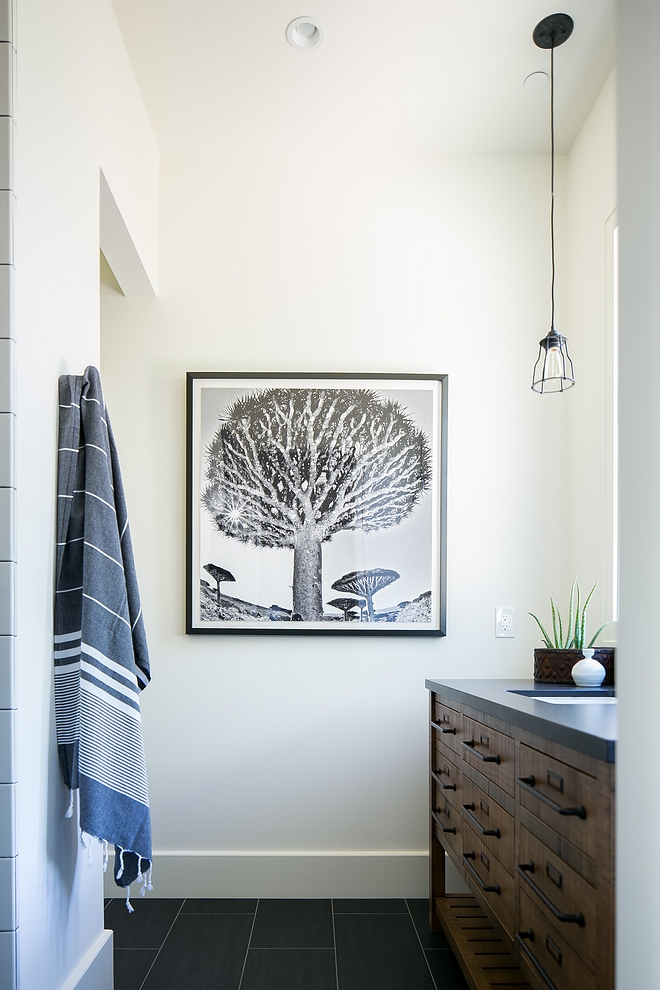 Bathroom featuring black and white artwork, black floor tile, white walls and an industrial vanity with leathered countertop #bathroom