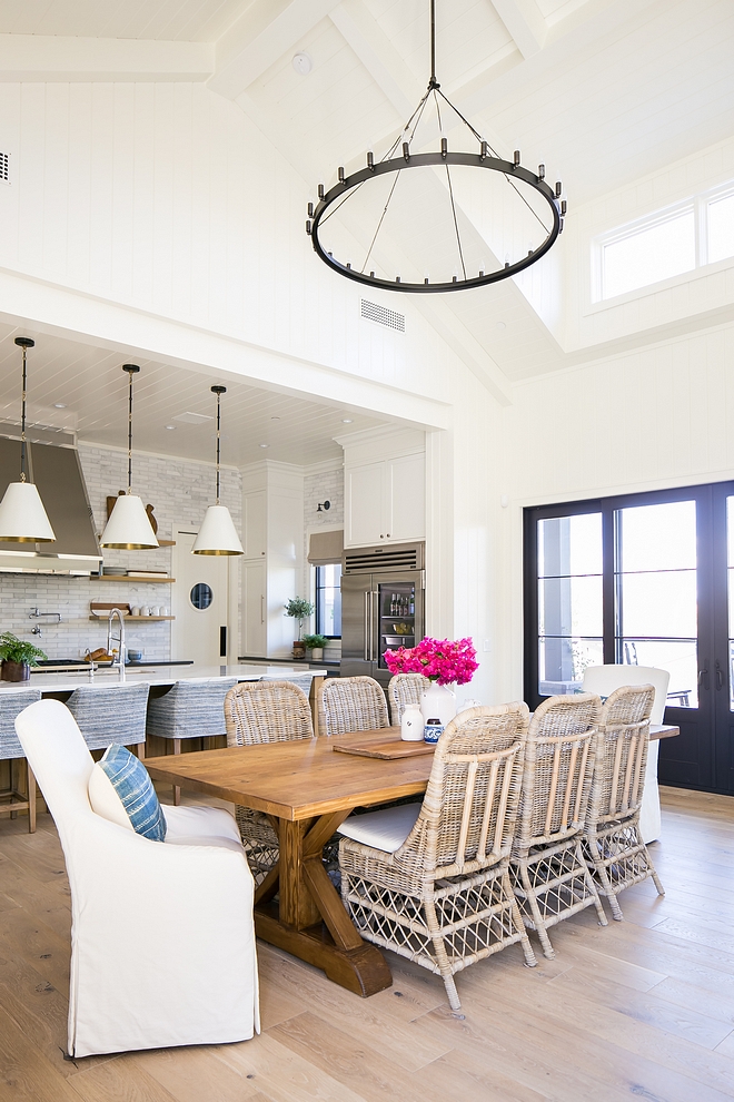 Casual dining room with high vaulted ceiling painted beams, white oak hardwood flooring with a matte sheen and black steel patio doors coordinates with a large wrought iron ring chandelier #diningroom #casualdiningroom