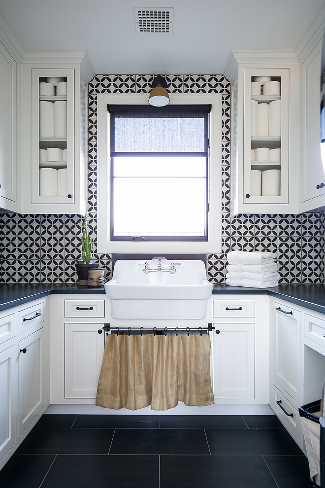 Black and white laundry room featuring white shaker cabinets, black countertop, black and white cement tile and an utility sink Black and white laundry room Black and white laundry room #Blackandwhitelaundryroom #laundryroom