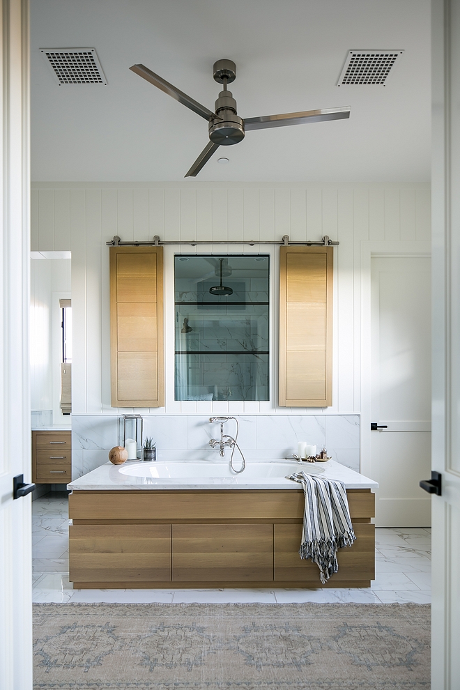 Bathroom featuring White Oak tub surround and shower White Oak shutters hung in barn door hardware #WhiteOak #tubsurround #bathroom