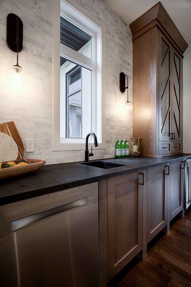 Butlers pantry with white oak shaker style cabinet with custom mullion in a Chevron pattern, slim marble subway tile and leathered black granite countertop #butlerpantry #whiteoakcabinet #cabinetmullion #shakerstylecabinet #marblesubwaytile #leatheredblackgranite