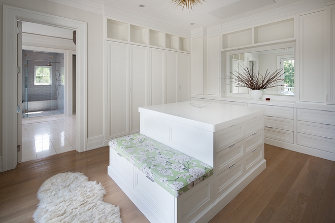 Dressing room Closet with custom cabinetry and island with built-in bench Paint color is Benjamin Moore White #Dressingroom #Closet #cabinetry #closetisland #builtinbench #BenjaminMooreWhite