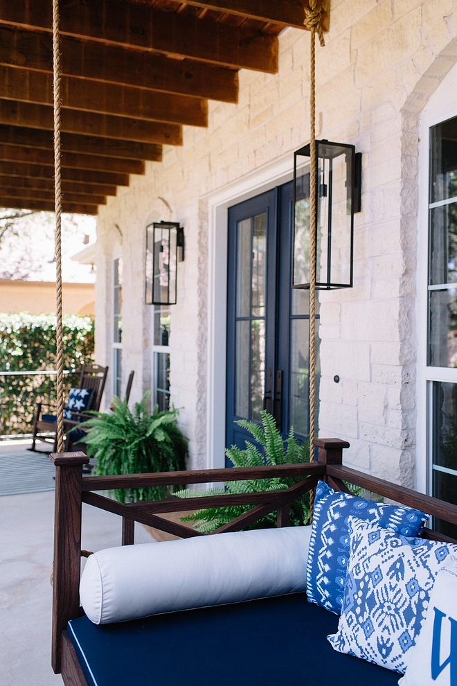 Porch Swing We installed a porch swing with navy blue and white accents. The seat is upholstered in a navy fabric with contrast pale blue piping. A mix of patterned pillows add some personality to the front porch. The dark stain wood frame and decorative siding of the bench gives a strong contrast to the front porch swing #porchswing