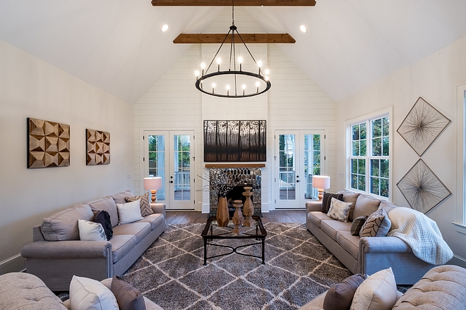 Farmhouse vibes start to really kick in With a full height shiplap accent wall it's hard to not just sit back, relax, and take it all in. Cedar exposed beams and a matching fireplace mantle help evoke a rustic feel The ceiling vaults to a grand scale of 20 feet, and that vault even continues outside to the covered porch